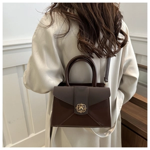 Close-up of a dark brown envelope tote with a vintage gold clover-style metal clasp buckle