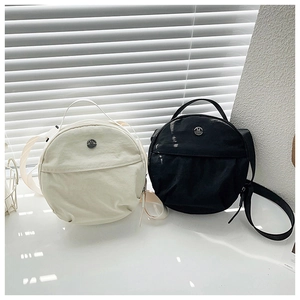 Close-up of minimalist round nylon crossbody bags with metal logo and shoulder straps