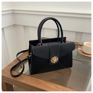Detail of black structured tote bag featuring a decorative golden rose shaped metal clasp