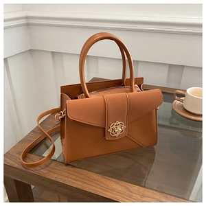Close-up of brown leather tote with a gold floral metal buckle on a minimalist table