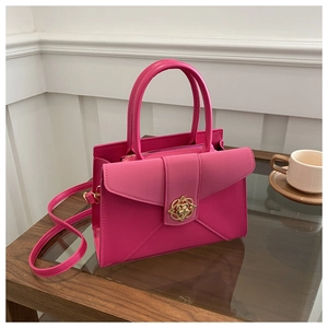 Close-up of rose red tote bag with golden petal clasp on a wooden coffee table