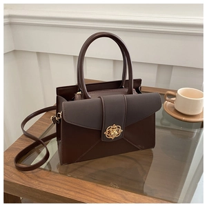 Detailed close-up of dark brown vintage tote bag with gold patterned buckle and leather texture