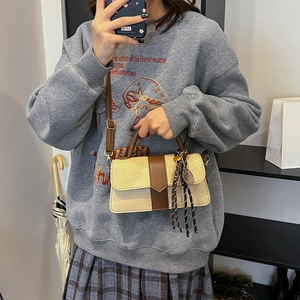 Retro patchwork crossbody bag in beige and brown with adjustable strap and decorative pendant