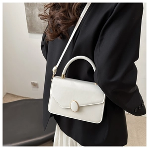 Detail der weißen eckigen Handtasche mit Goldmagnetverschluss und elegantem Griff