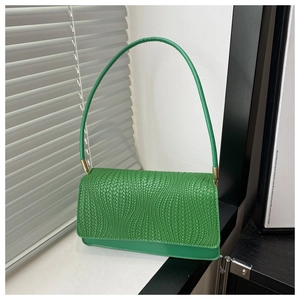 Close-up of bright green woven texture and golden hardware on the small shoulder bag