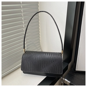 Detail of black woven shoulder bag featuring textured wave pattern and thin cylindrical strap