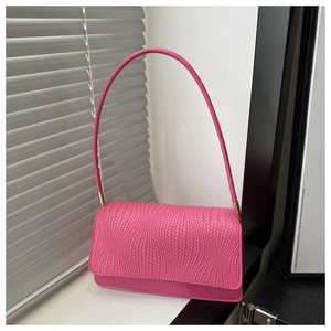 Detail of rose pink faux leather handbag with woven texture and gold metal hardware