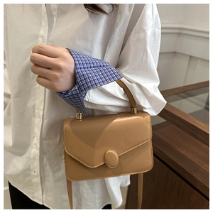 Dettaglio ravvicinato della borsa kaki con elegante chiusura ovale in metallo dorato