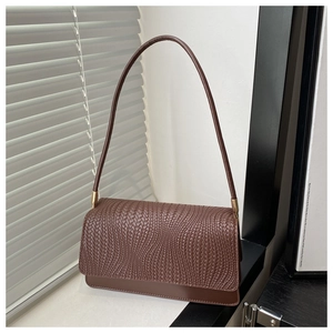 Close-up of dark brown woven texture shoulder bag with gold hardware detail
