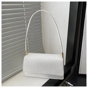 Detail of white baguette bag showing intricate woven texture and gold hardware accents