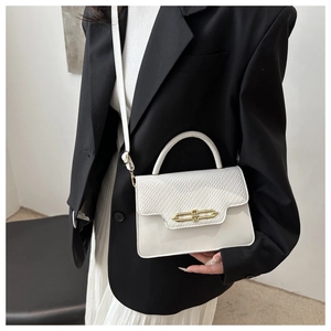 Close-up of a white textured flap handbag with a gold-tone metal ring lock and top handle