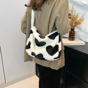 Fuzzy heart print tote bag in black and white faux fur shown on model's shoulder