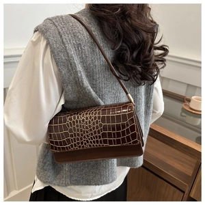 Detail of a brown crocodile pattern shoulder bag on model with vintage aesthetic style