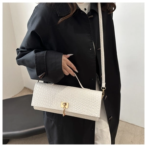 Dettaglio di una borsa baguette bianca in pelle intrecciata con chiusura a scatto dorata
