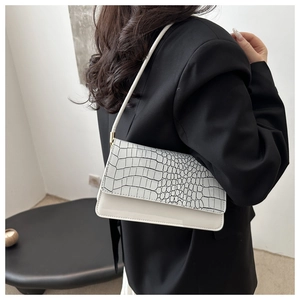 Detailed view of white shoulder bag featuring contrast black and white crocodile texture