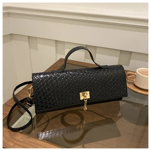 Detail of woven texture and gold square clasp on black faux leather baguette bag