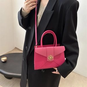 Hot pink tote bag with golden flower buckle shown on model in black suit jacket