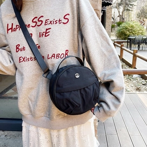 Minimalist black round nylon crossbody bag with dual zippers and top handle for women