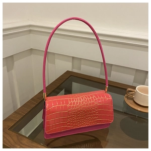 Detail of pink baguette bag featuring crocodile texture flap and gold hardware accents