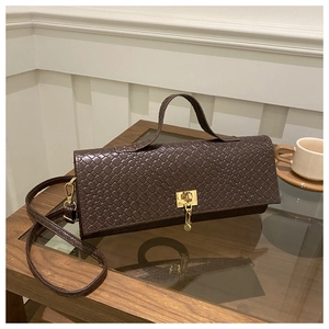 Close-up of dark brown woven leather baguette bag with elegant gold metal clasp and strap