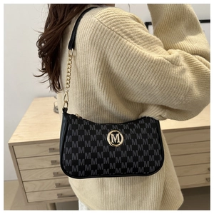 Close-up of black monogram shoulder bag with gold metal M logo and chain detail