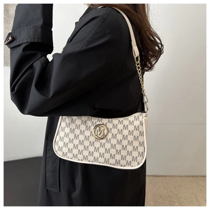 Detail of crescent shoulder bag with beige M-pattern print and gold logo accent