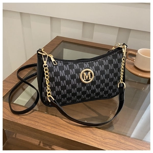 Detail of grey monogram letter pattern with golden M logo on stylish shoulder bag
