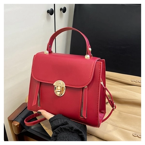 Détail du sac à main rouge montrant le fermoir doré et les fermetures décoratives