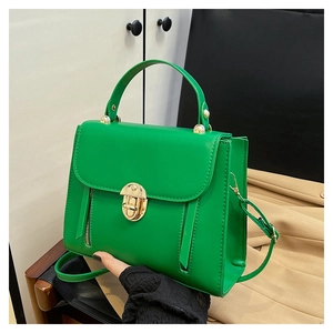 Gros plan détaillé du sac à main en cuir vert avec fermoir doré et poignée chic
