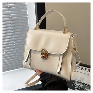 Détail du sac à main en similicuir blanc cassé avec fermoir rotatif doré et poignée supérieure