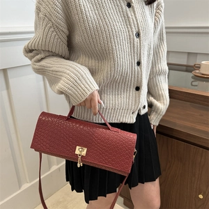 Deep red crocodile embossed baguette bag with golden buckle shown on a model