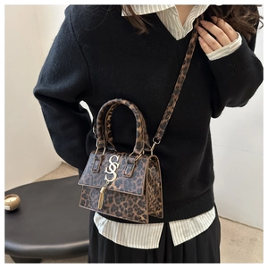 Detail of leopard print crossbody bag with gold SS logo and tassel on a model