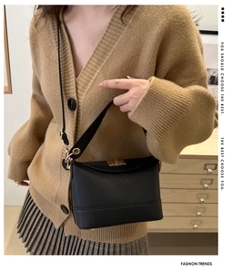 Detail of black lychee grain leather handbag featuring a golden twist lock closure