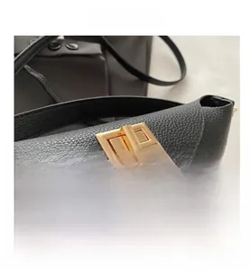 Close-up of golden rectangle twist-lock on black lychee grain leather handbag detail