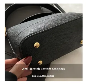 Close-up of black lychee leather bag bottom featuring four protective gold metal studs