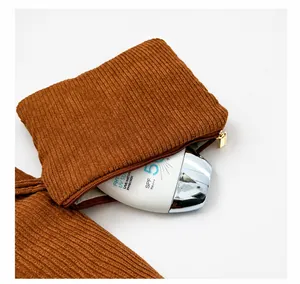 Detailed view of a brown corduroy mini pouch with golden zipper and sunblock storage