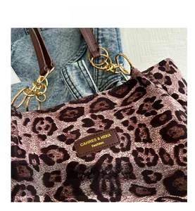 Detail of leopard print tote bag featuring brown leather logo tag and gold metal chain strap