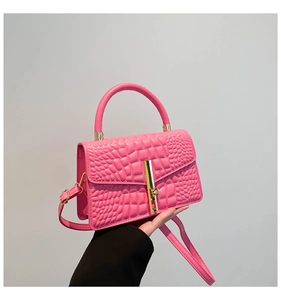 Detailed shot of pink croc-embossed handbag with gold hardware and top handle