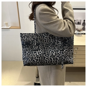 Detailed side view of a large leopard print tote bag worn on a woman shoulder
