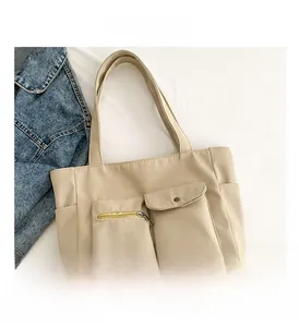 Detail view of khaki nylon tote bag featuring front zipper and flap snap closure pockets