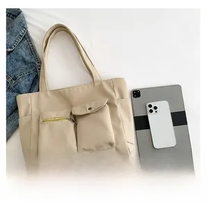 Detail view of large nylon tote bag with functional pockets beside tablet and jacket