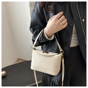 Detail of cream leather bucket bag featuring a gold twist lock and crossbody strap