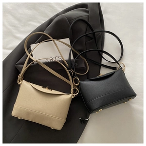Detail of beige and black litchi grain leather crossbody bags with gold metal clasps