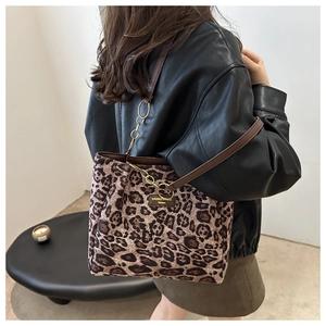 Detail of leopard print tote bag with brown leather straps and gold metal chain links