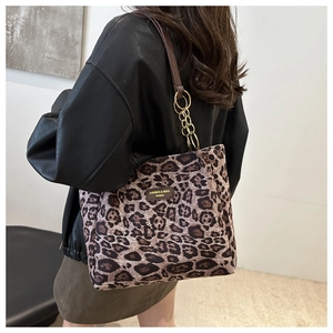 Detail of leopard print tote bag featuring a gold chain strap and leather handles