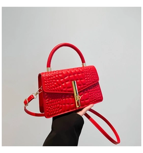 Close-up of red crocodile pattern leather handbag with gold metal clasp detail