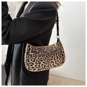 Detail of leopard print hobo bag with gold zipper closure on shoulder of model