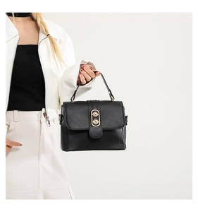 Dettaglio di elegante borsa a mano in pelle nera opaca con chiusura dorata