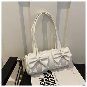 Detalle de un bolso cilíndrico blanco crema con elegantes adornos de lazos en 3D