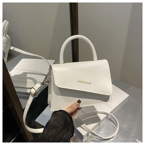 Close-up of a white minimalist handbag featuring asymmetric flap and gold lettering details